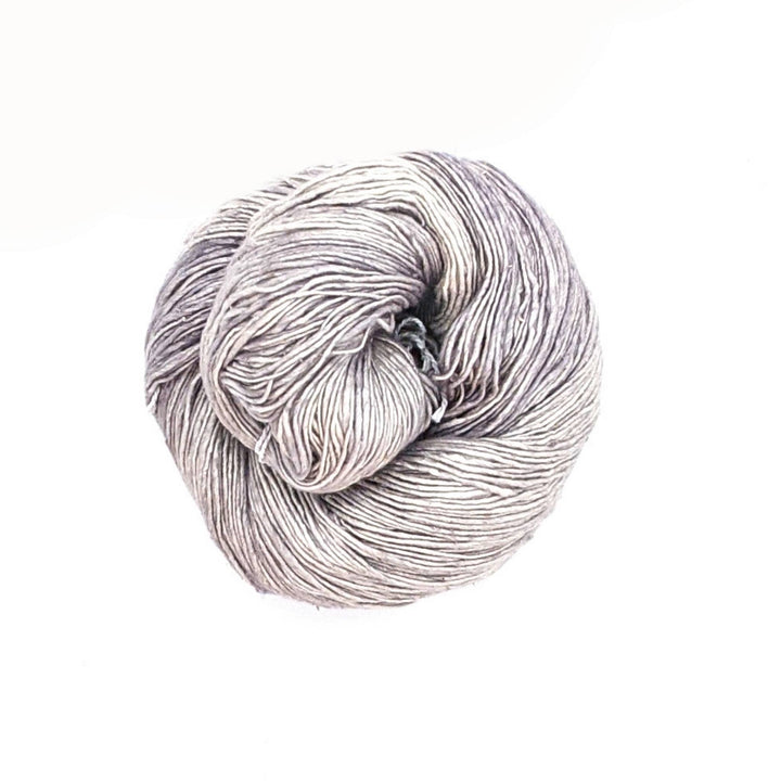 Lace weight silk yarn in color way ultimate grey in front of white background.