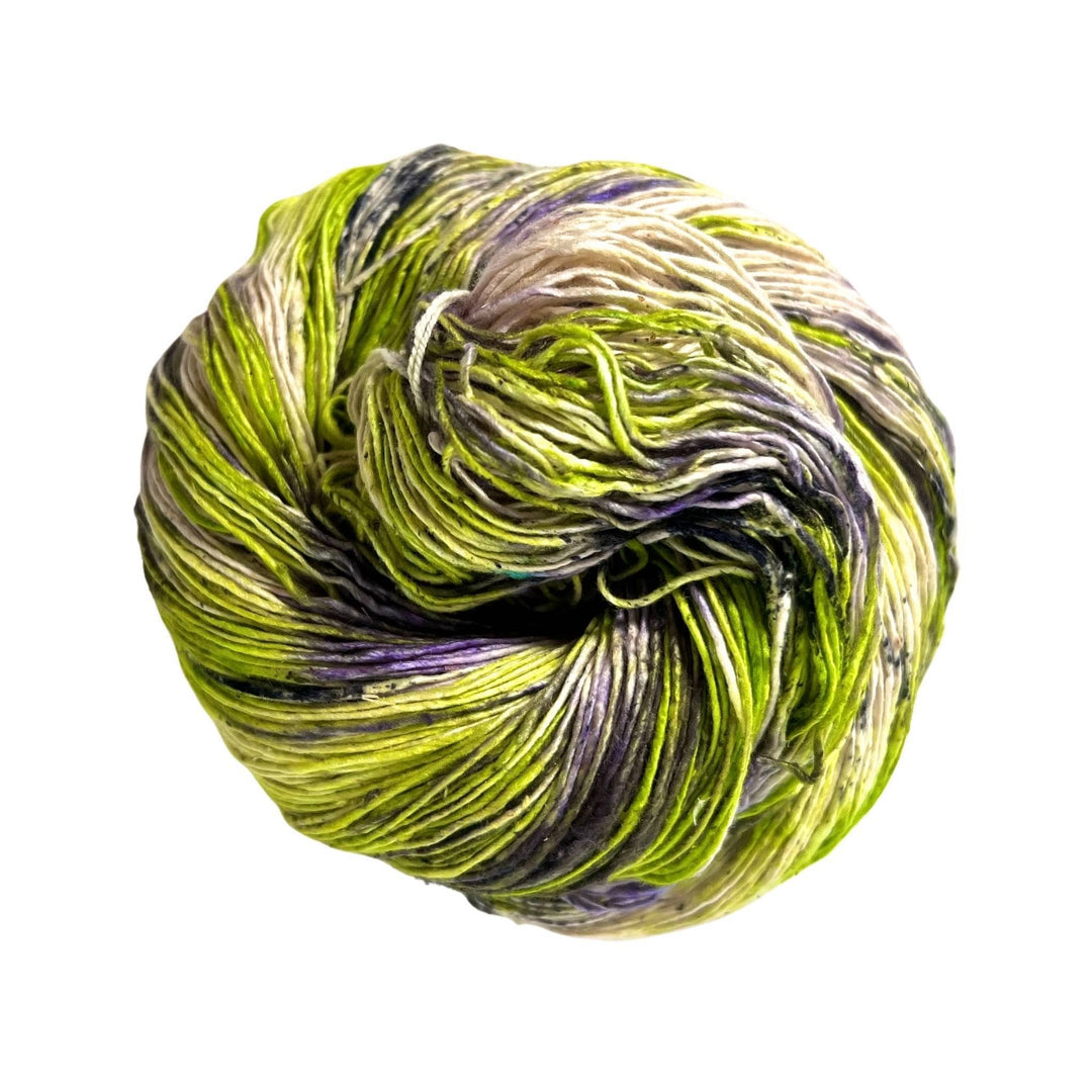 A skein of green lace weight silk yarn with splashes of purple and black on white background