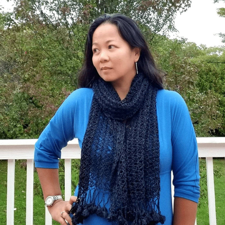 Woman wearing a blue shirt outside with a black shawl on
