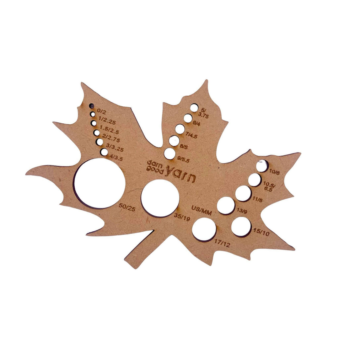 A wooden measuring gauge in the shape of a leaf on a white background.