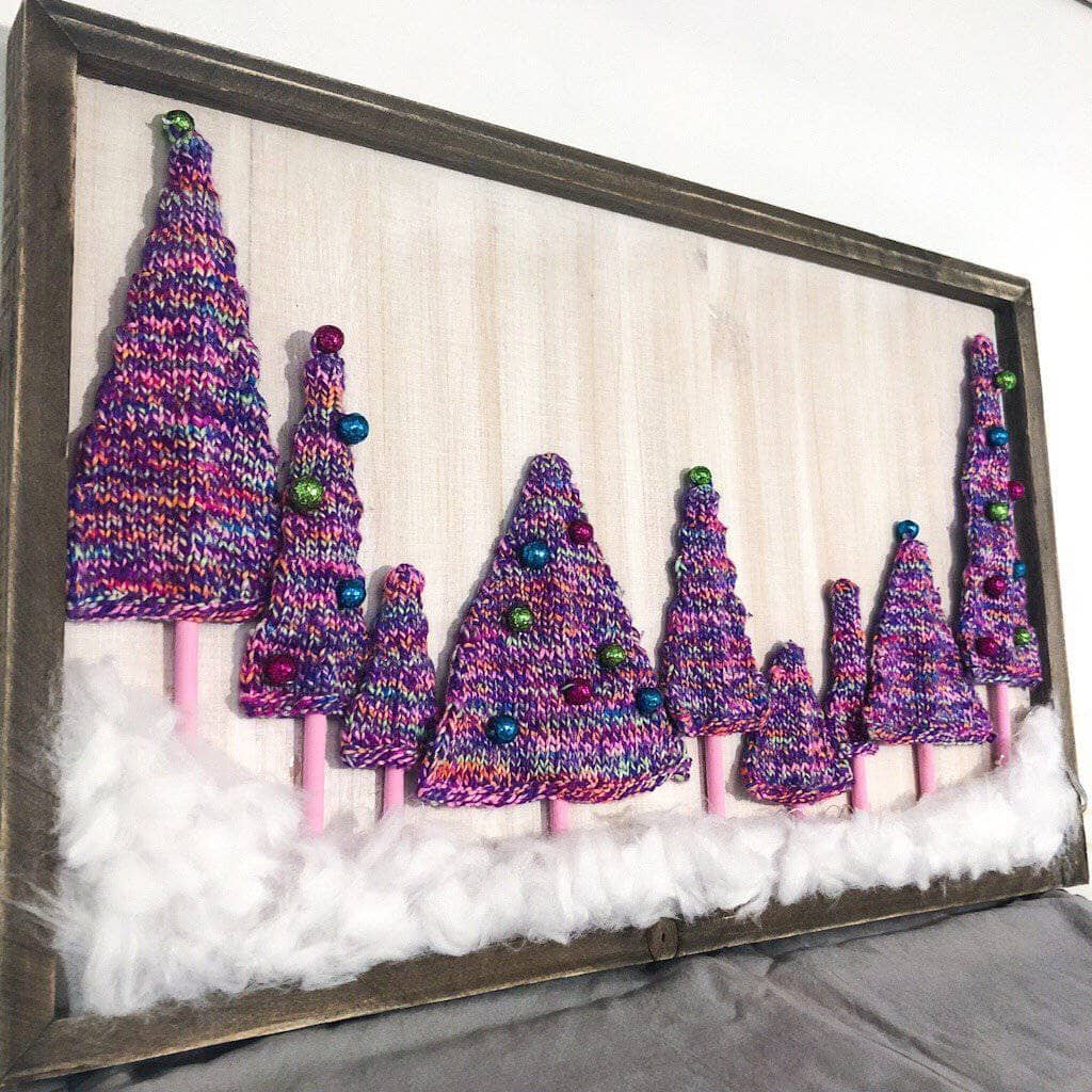 angled view of knit multicolor trees arranged in a frame to resemble a magical forest in front of a white background.