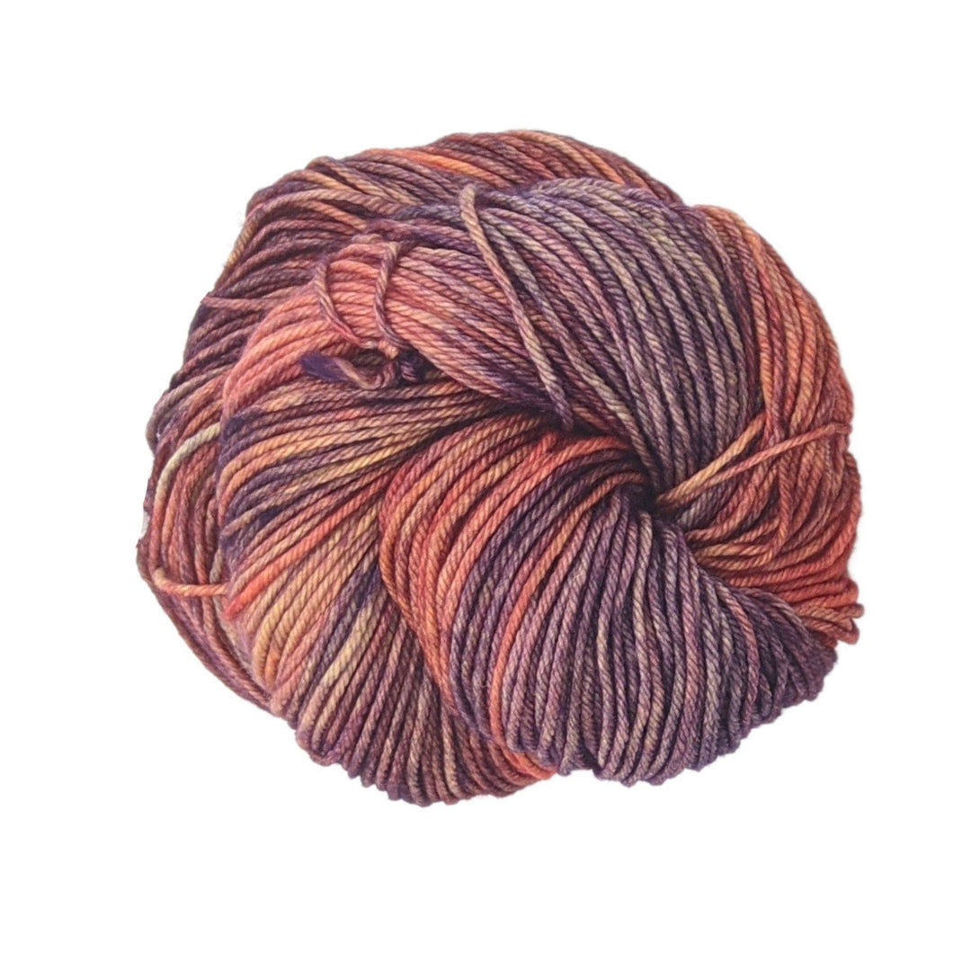 Skein of tonal orange and purple yarn in front of a white background. 