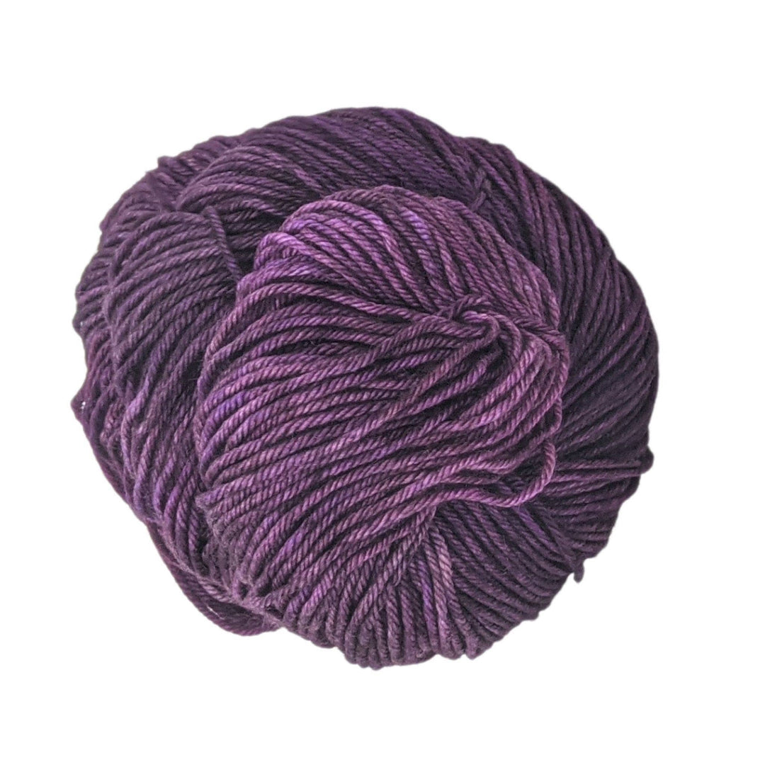 Skein of tonal purple yarn in front of a white background. 