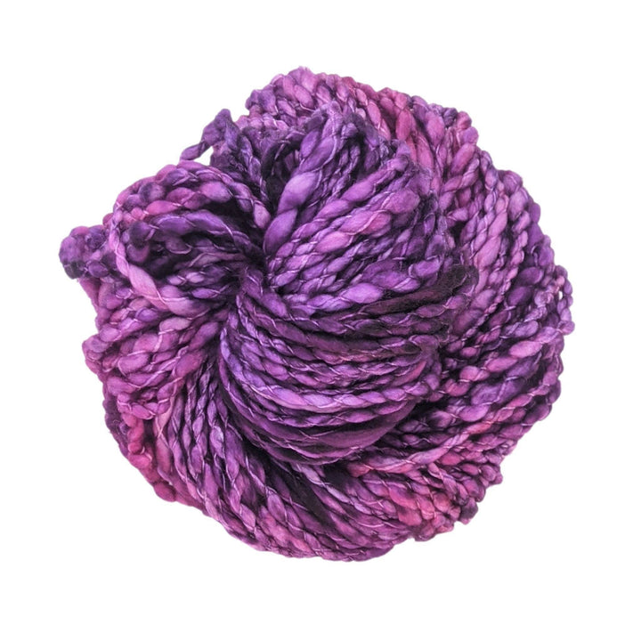 Skein of tonal purple yarn in front of a white background