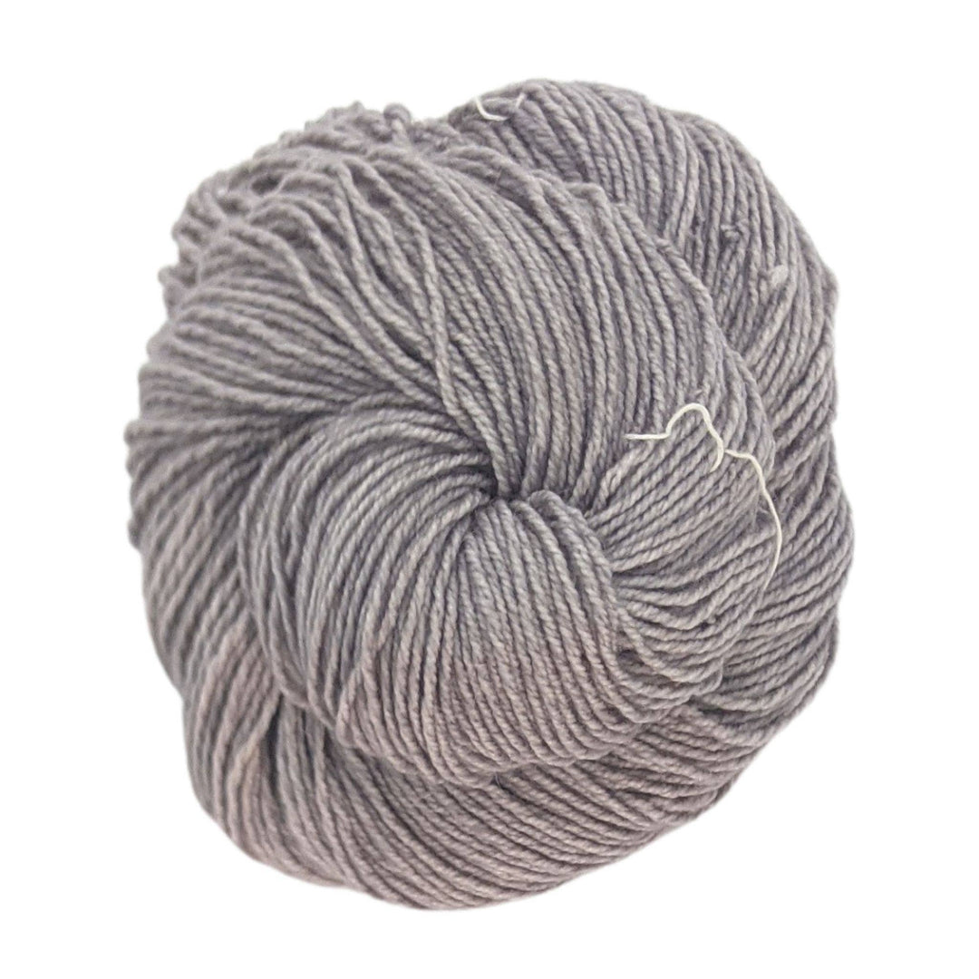 Skein of grey yarn in front of a white background.
