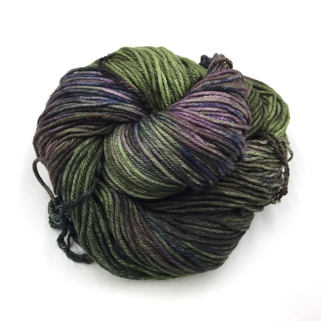 close up of a cake of yarn in the color zarzamora (green and purple)