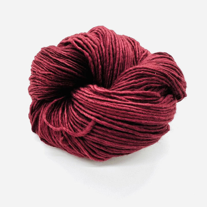 A burgundy worsted weight skein of yarn on a white background