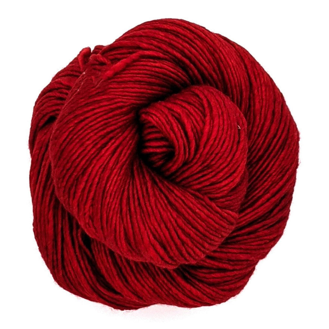 Red cake of yarn in Raverly Red on a white backdrop. 