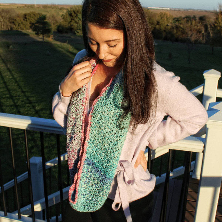 woman looking down wearing a colorful crochet scarf