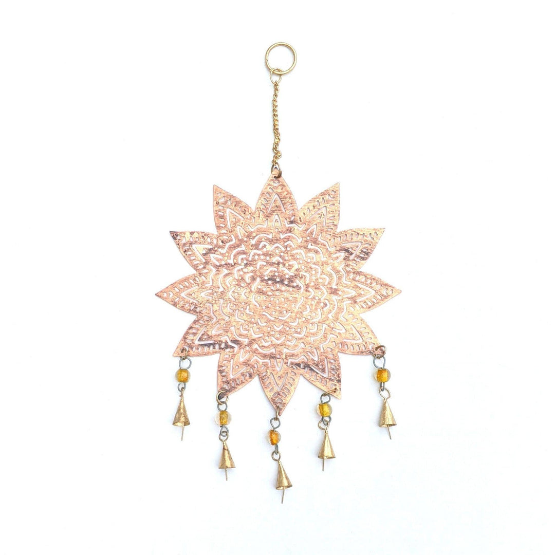Copper plated metal mandala chime in front of a white background.