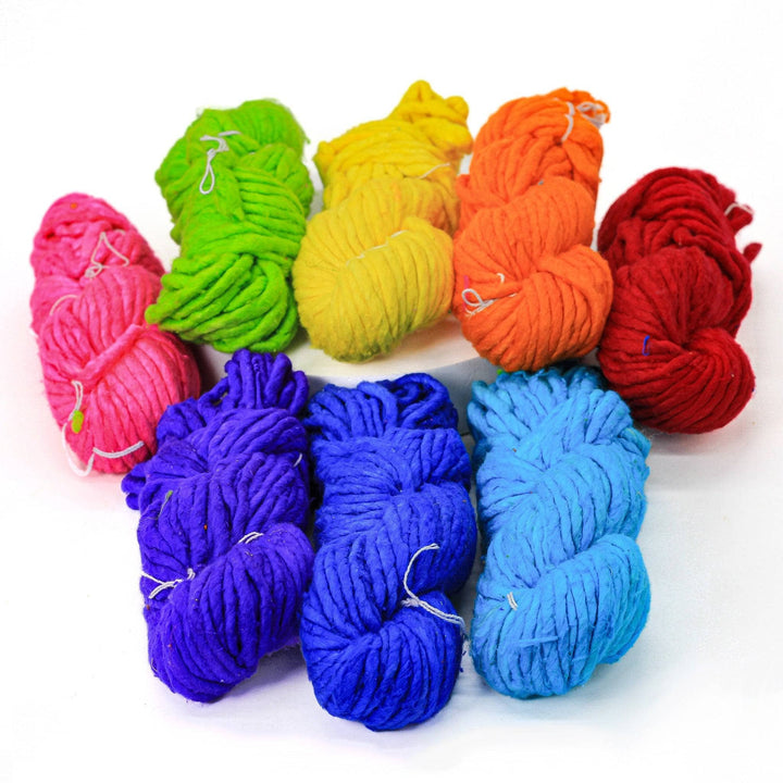 Super bulky weight single ply recycled silk yarn multicolor pack in front of a white background. From left to right: pink, lime green, yellow, orange, red, purple, dark blue, light blue.