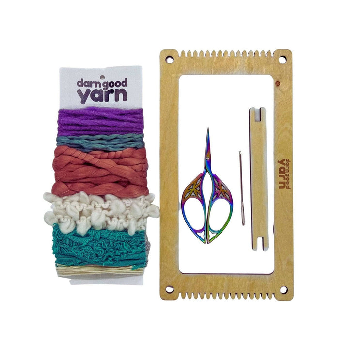 weaving kit flat lay showing contents of loom darning needle mini heddle scissors and yarn