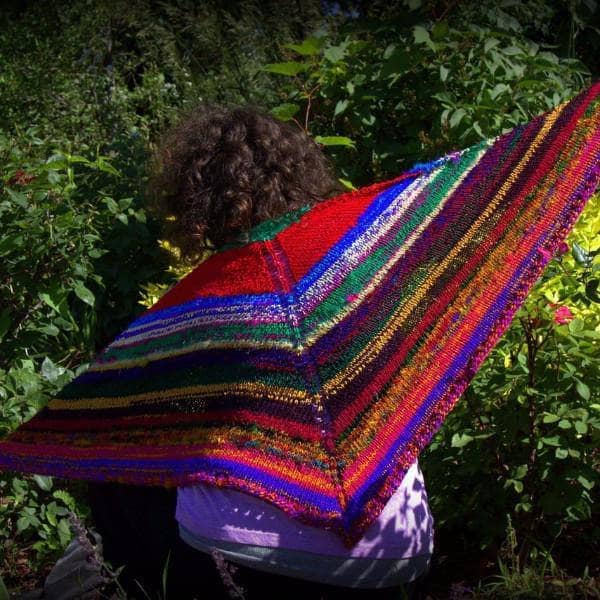 back of a woman wearing colorful red yellow blue and brown shawl