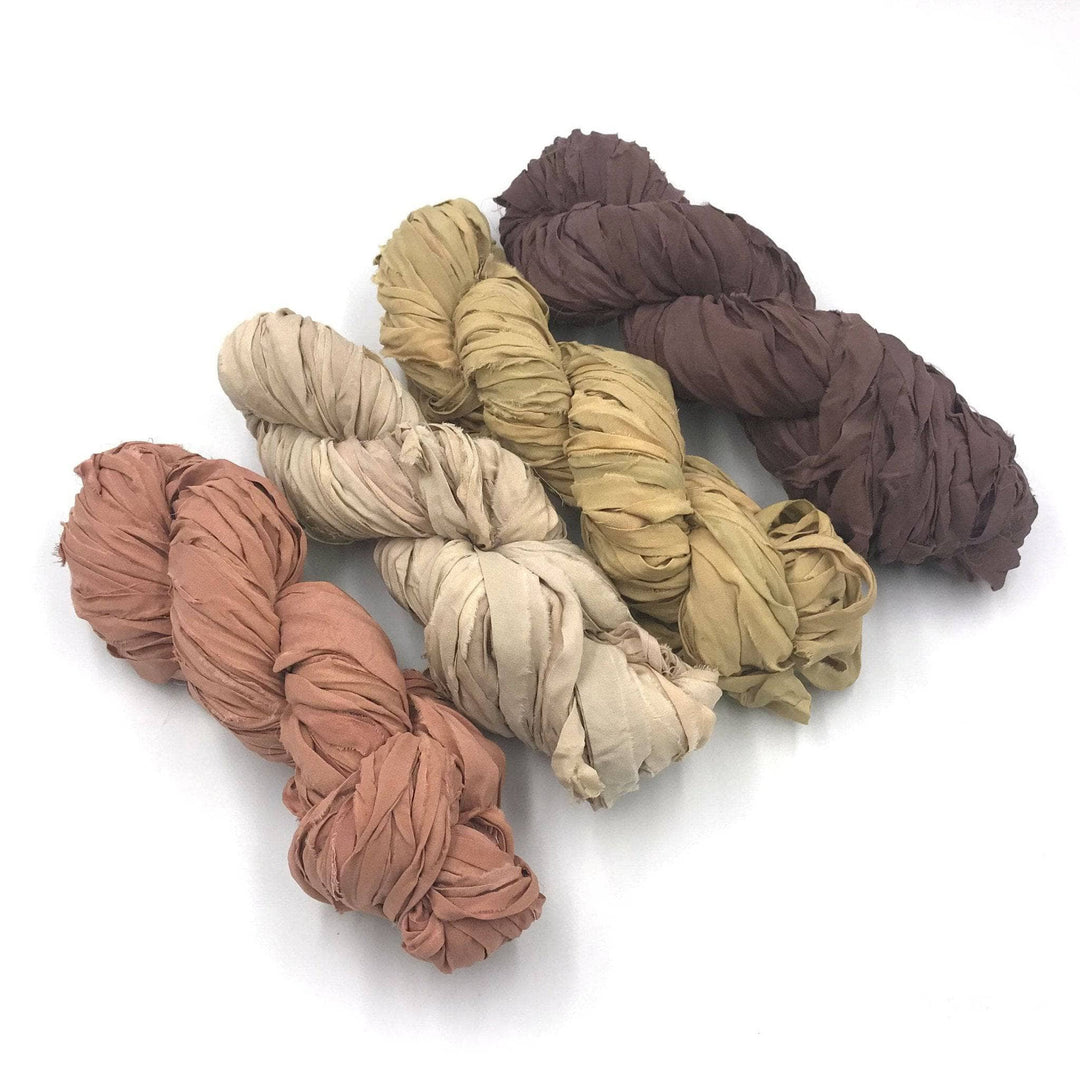 4 skeins of tan and brown ombre ribbon yarn on a white background