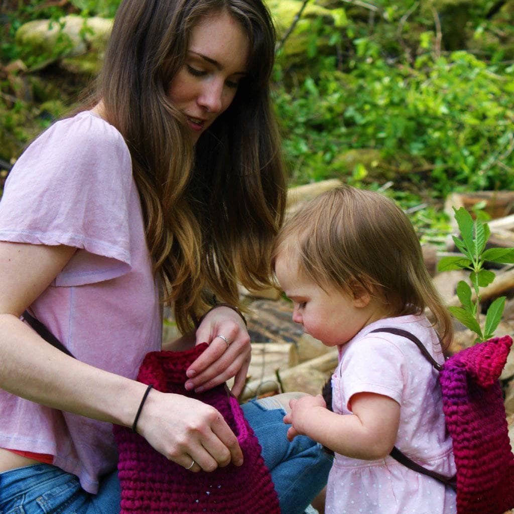 mom and child wearing a pink bag in a garden 