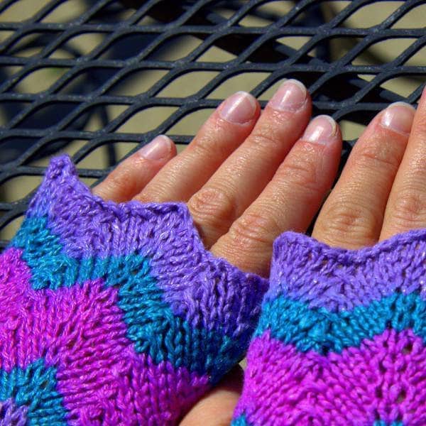 close up of hands wearing  purple green and pink mittens