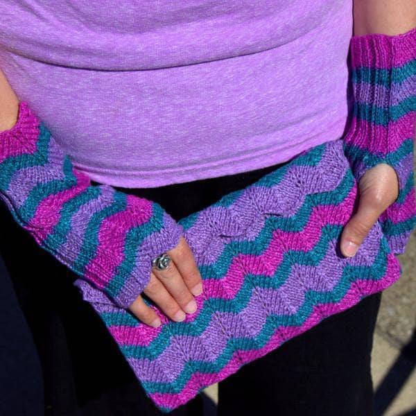 woman with purple green and pink mittens holding a purple green and pink clutch