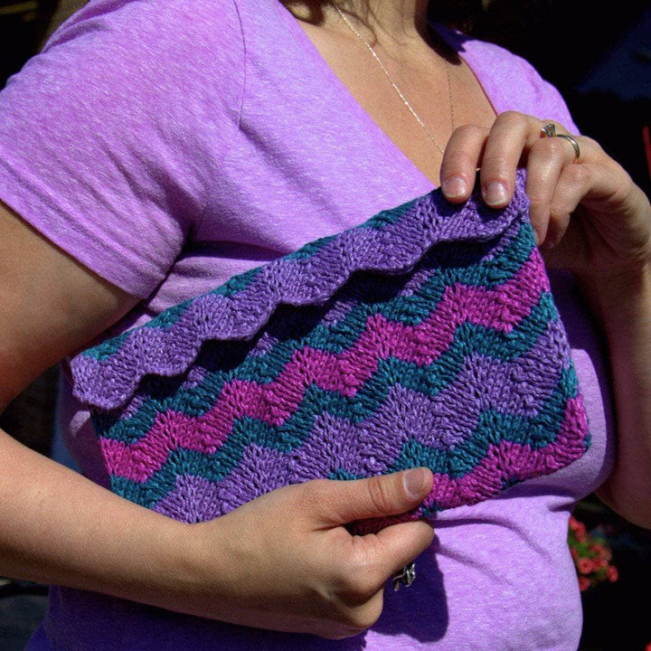 woman holding a purple green and pink clutch
