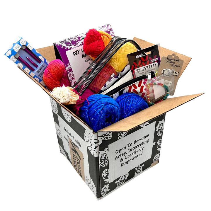 An open mystery black box with craft supplies pouring out of the top.