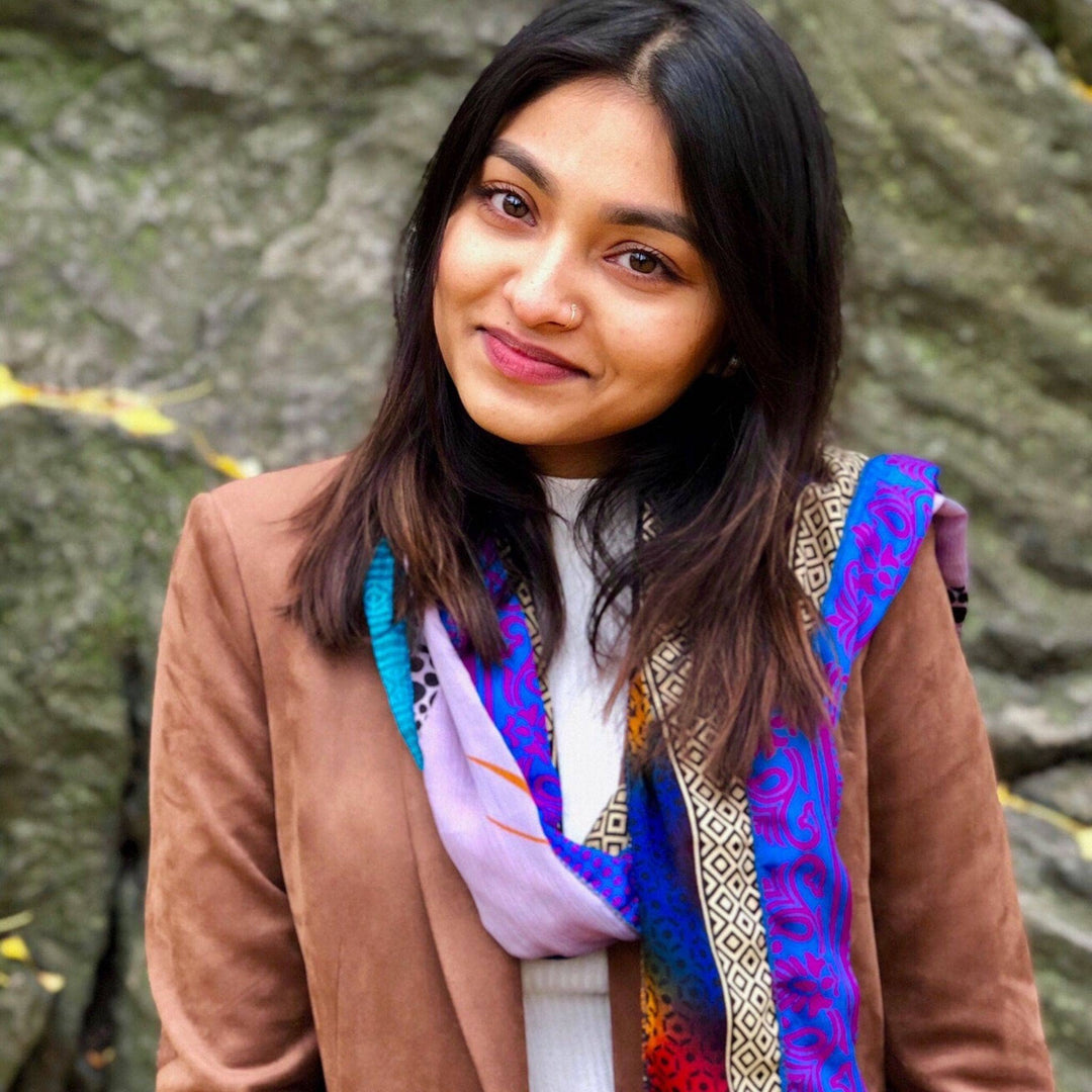 Model wearing sari silk medley scarf (multicolor) while standing outside with rock in the background.