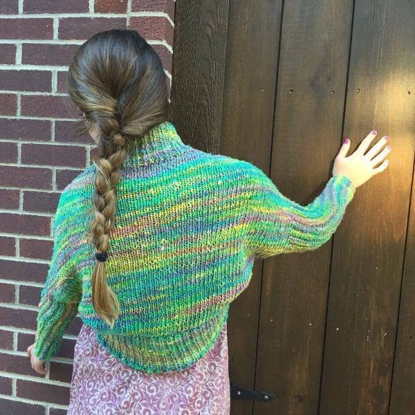 back of a woman wearing a colorful green and yellow Shrug