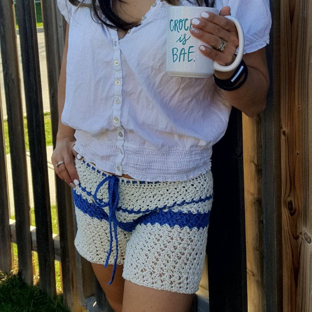 woman wearing crochet top with a white shirt and holding a mug