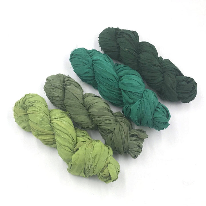 four skeins of ombre green yarn with a white background
