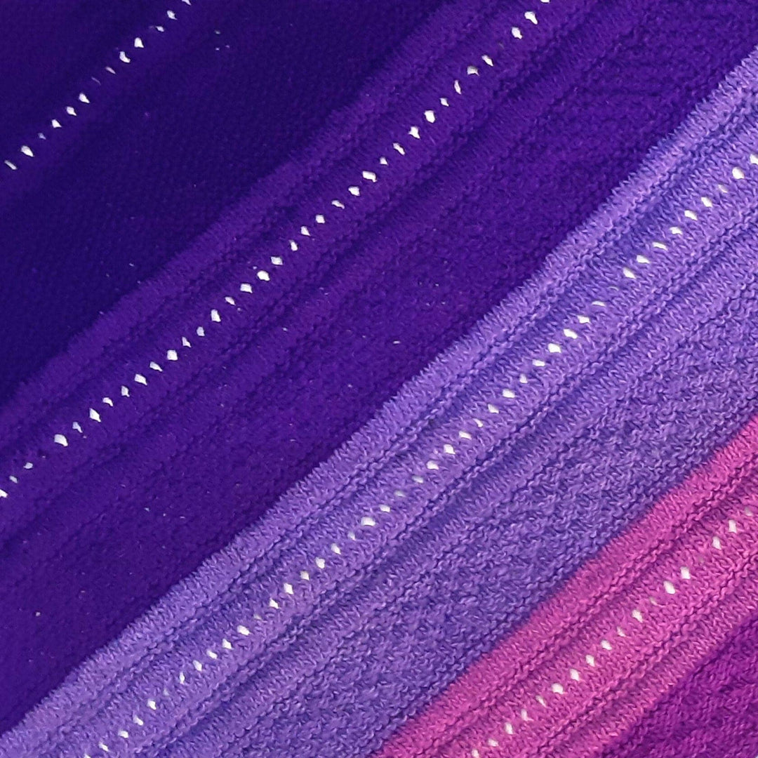 Closeup of stitches in ombre stitch sampler shawl purple in front of a white background. 