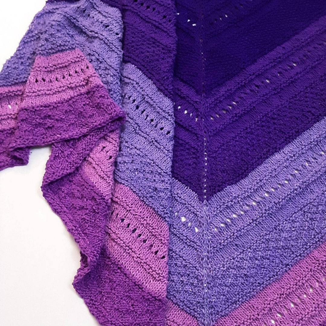 Closeup of stitches in ombre stitch sampler shawl purple in front of a white background.