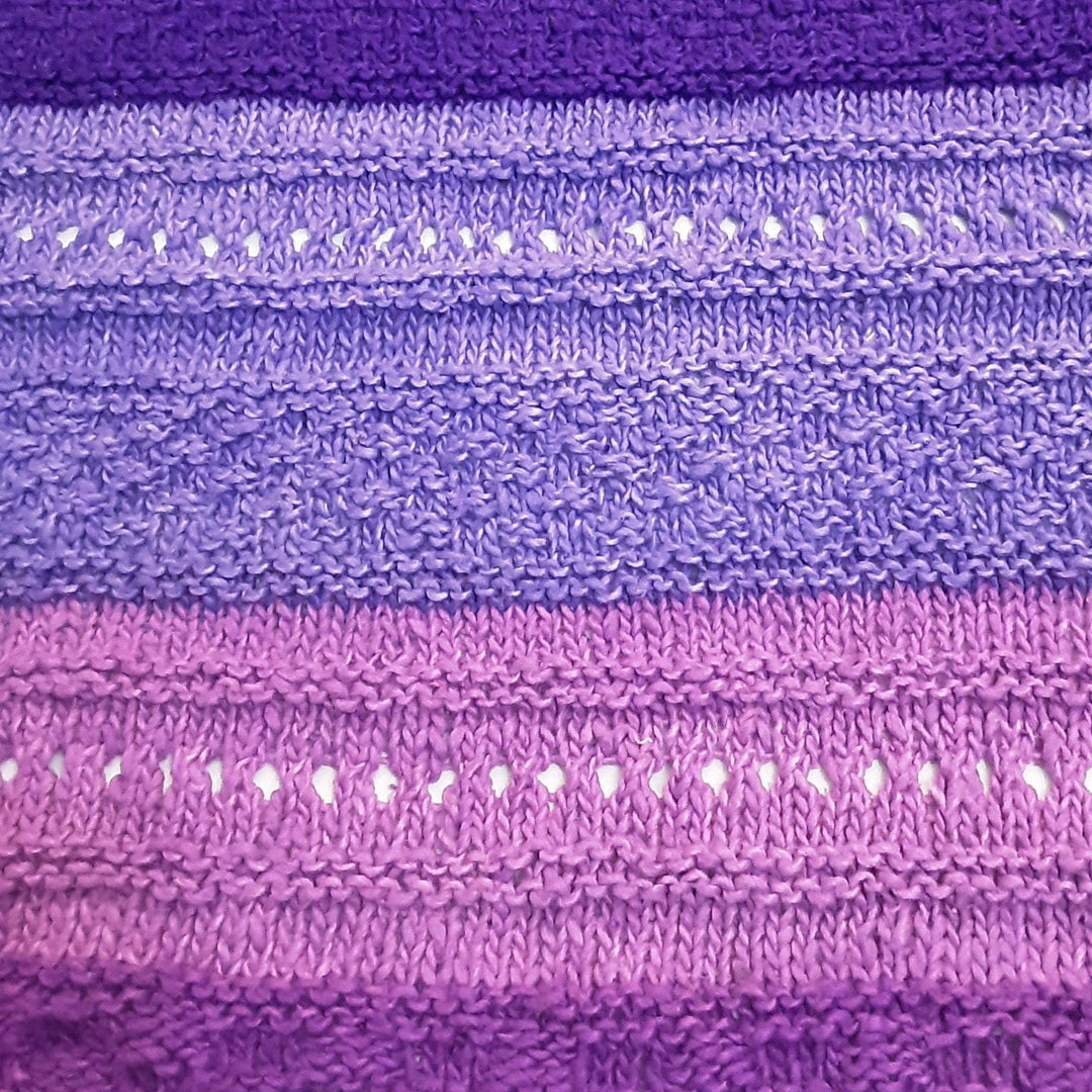 closeup of stitched in ombre stitch sampler shawl purple in front of a white background.