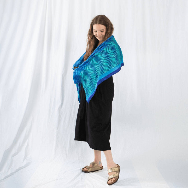 Model is front of a white sheet backdrop with a one of a kind sari scarf over their shoulders. 