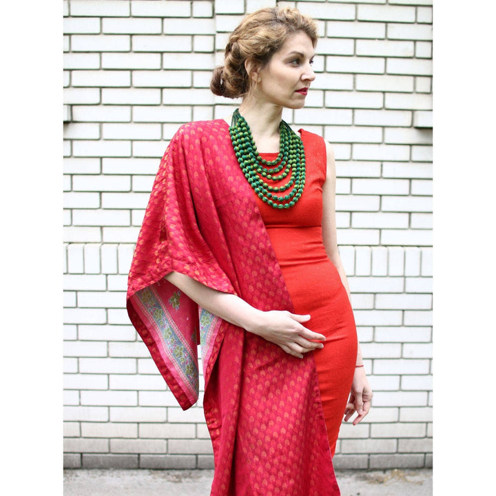 Model wearing one of a kind sari short scarf in red with white brick wall in the background.