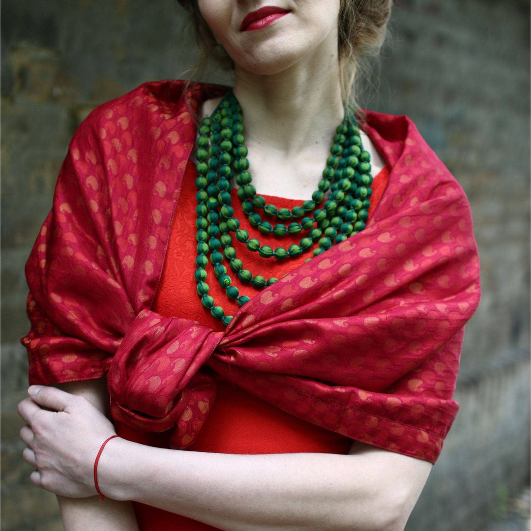 closeup of model wearing one of a kind sari scarf in red with unfocused brick wall in the background