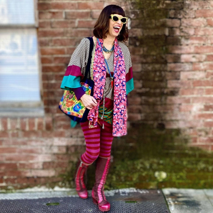 woman in front of brick wall in colorful outfit and pink boots