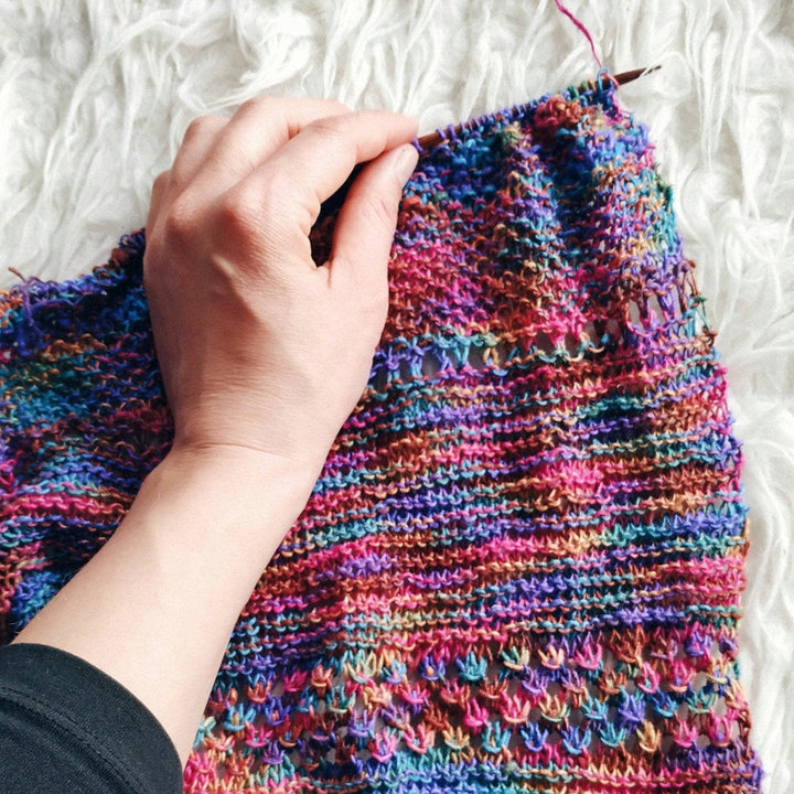 inprogress pink, purple , blue, brown knit shawl on a white background
