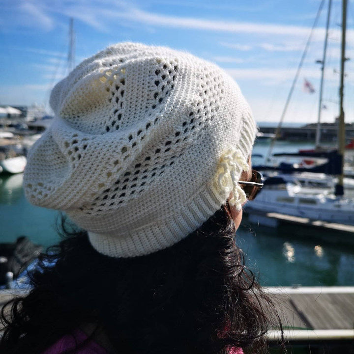 A women wearing a white beanie outside with boats in the background