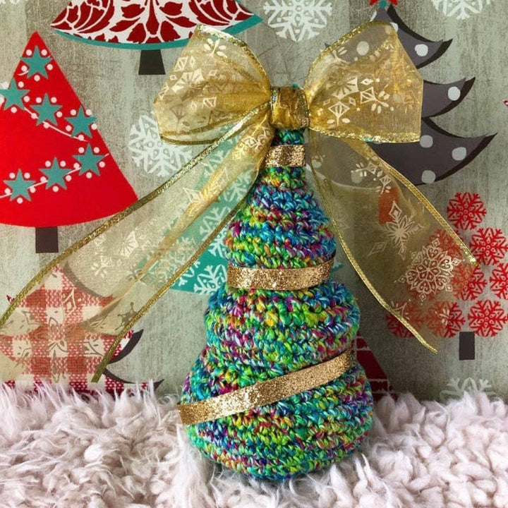 crochet Christmas Tree with a golden bow on top a white rug