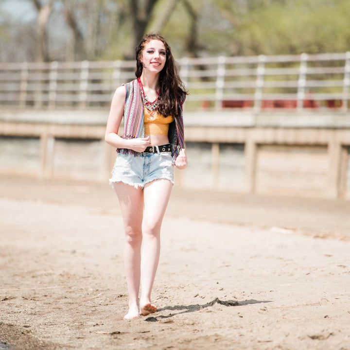 Model walking on the beach wearing the lavender heather bolero fringe vest 
