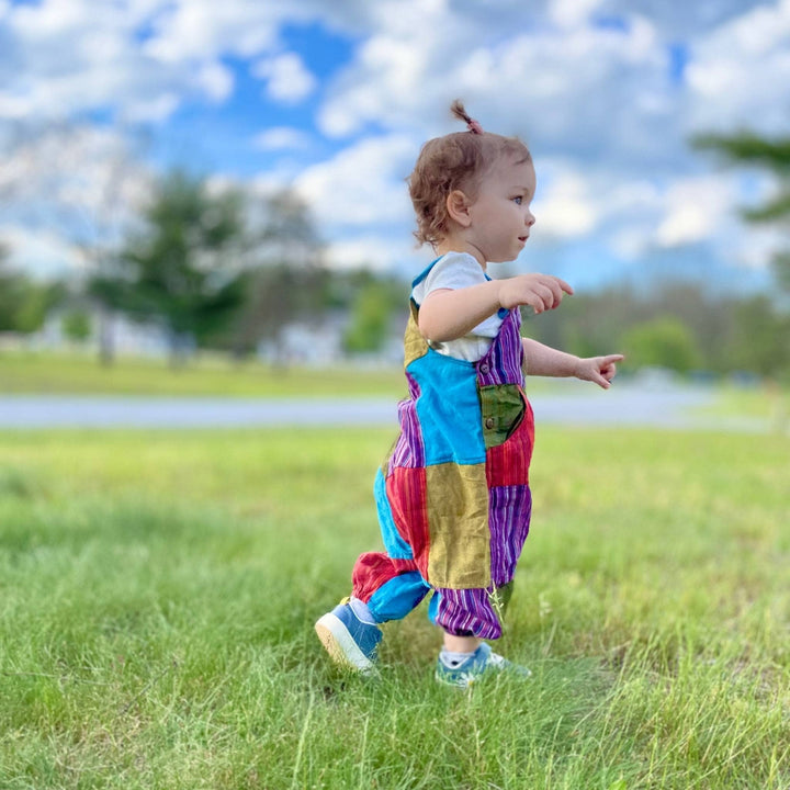 Toddler walking in the grass wearing the medium patchwork play pants.  