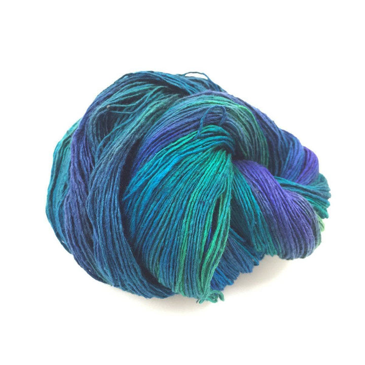 cake of yarn in the color enchanted forest (teal and purple) with a white background