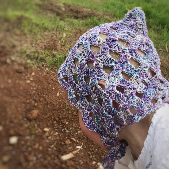 small child wearing a purple beanie looking down