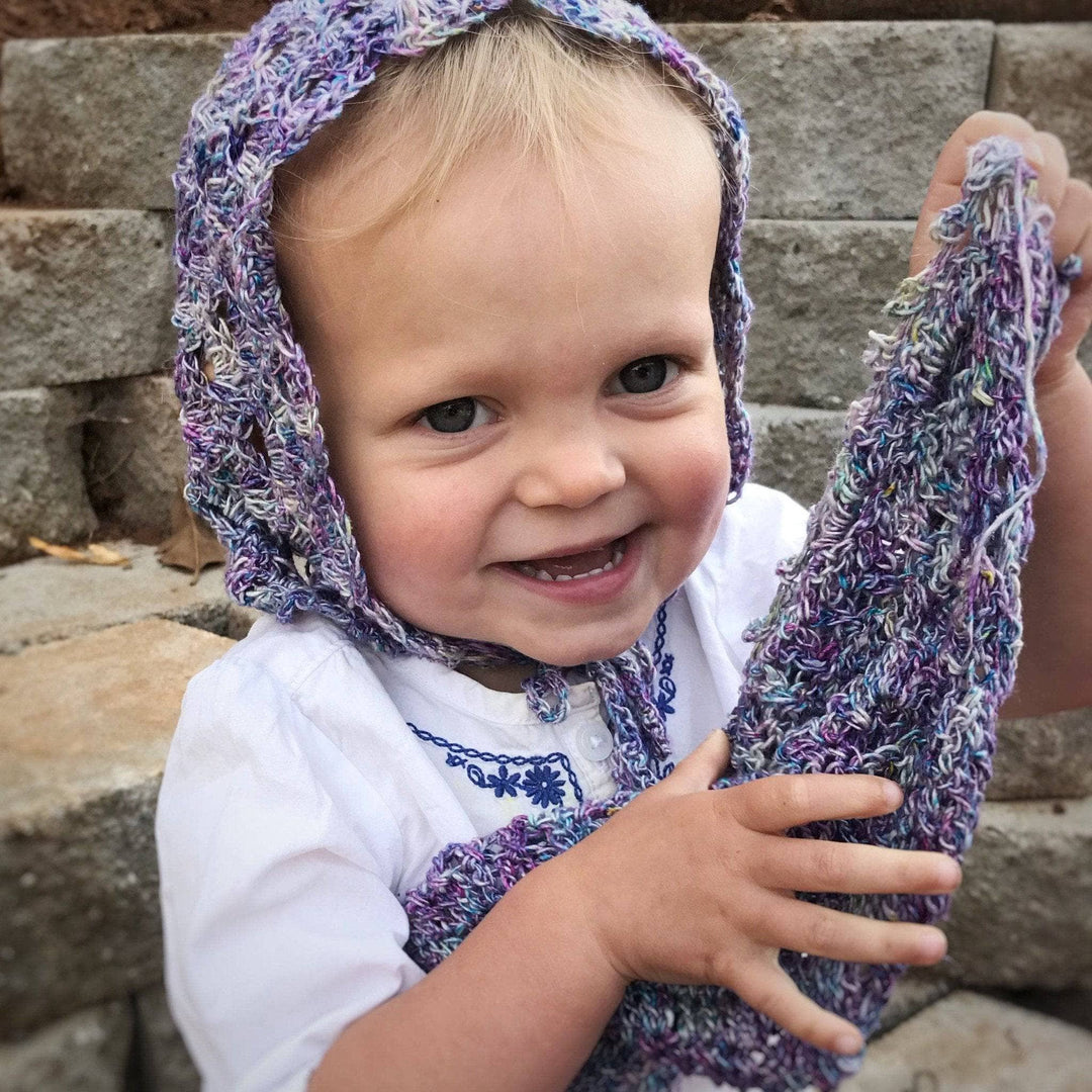 small child wearing a purple beanie and smiling at the camera