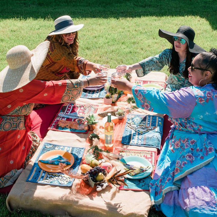 A group of models sitting around a picnic with ocean waves and spice market placemats in front of them on the table. 