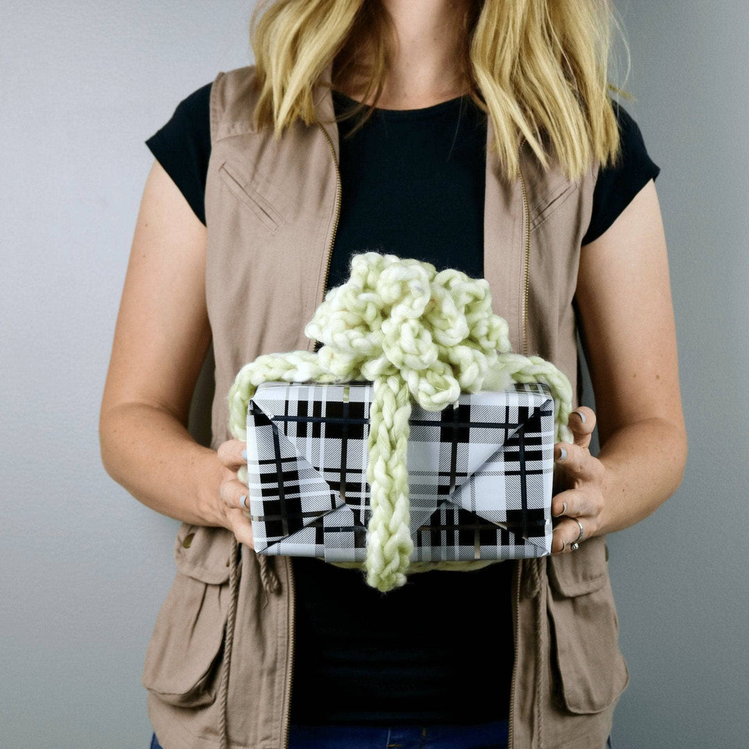 person holding a green yarn gift bow on a present