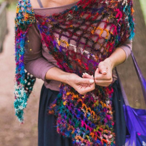 woman standing outdoor with a colorful shawl in her arms 