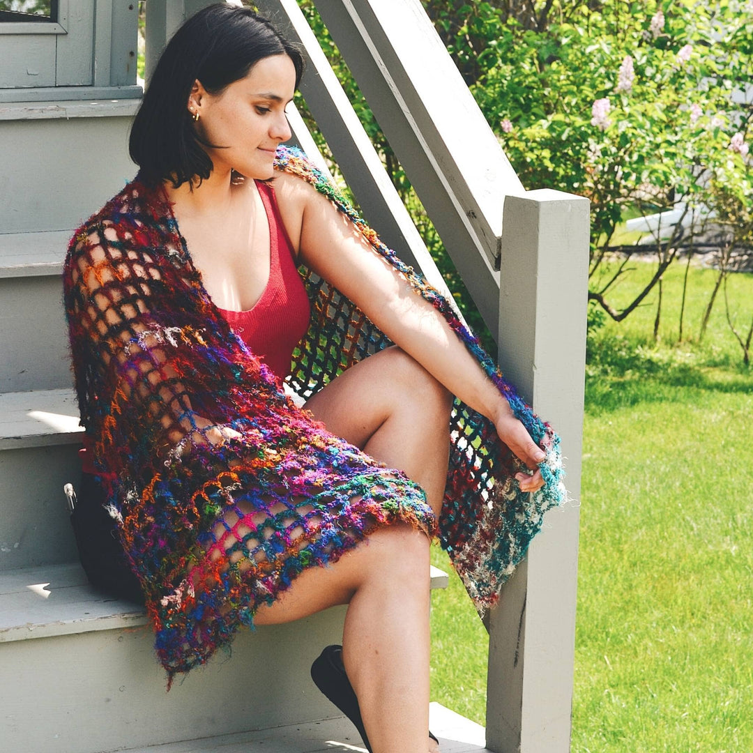 Model sitting on porch steps wearing quadramesh shawl made from recycled sari.