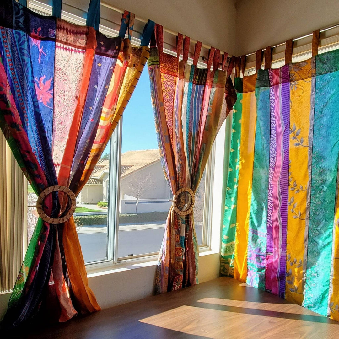 Recycled Sari Curtain Drapes hanging in a well lit room. Drapes are tied up in the middle with a wooden tieback. 