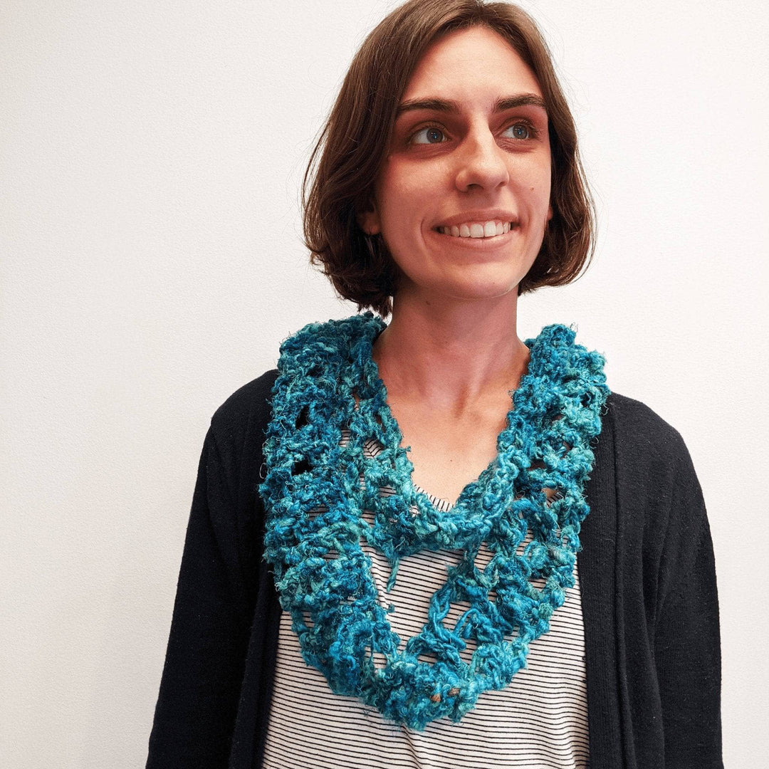 Model wearing rainy day infinity scarf in blue in front of a white background.