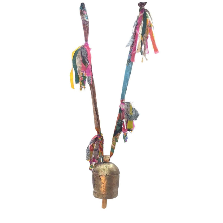 Brassy colored bell with wooden clapper, hanging from a colorful sari ribbon with 4 fringe tassels in front of a white background.