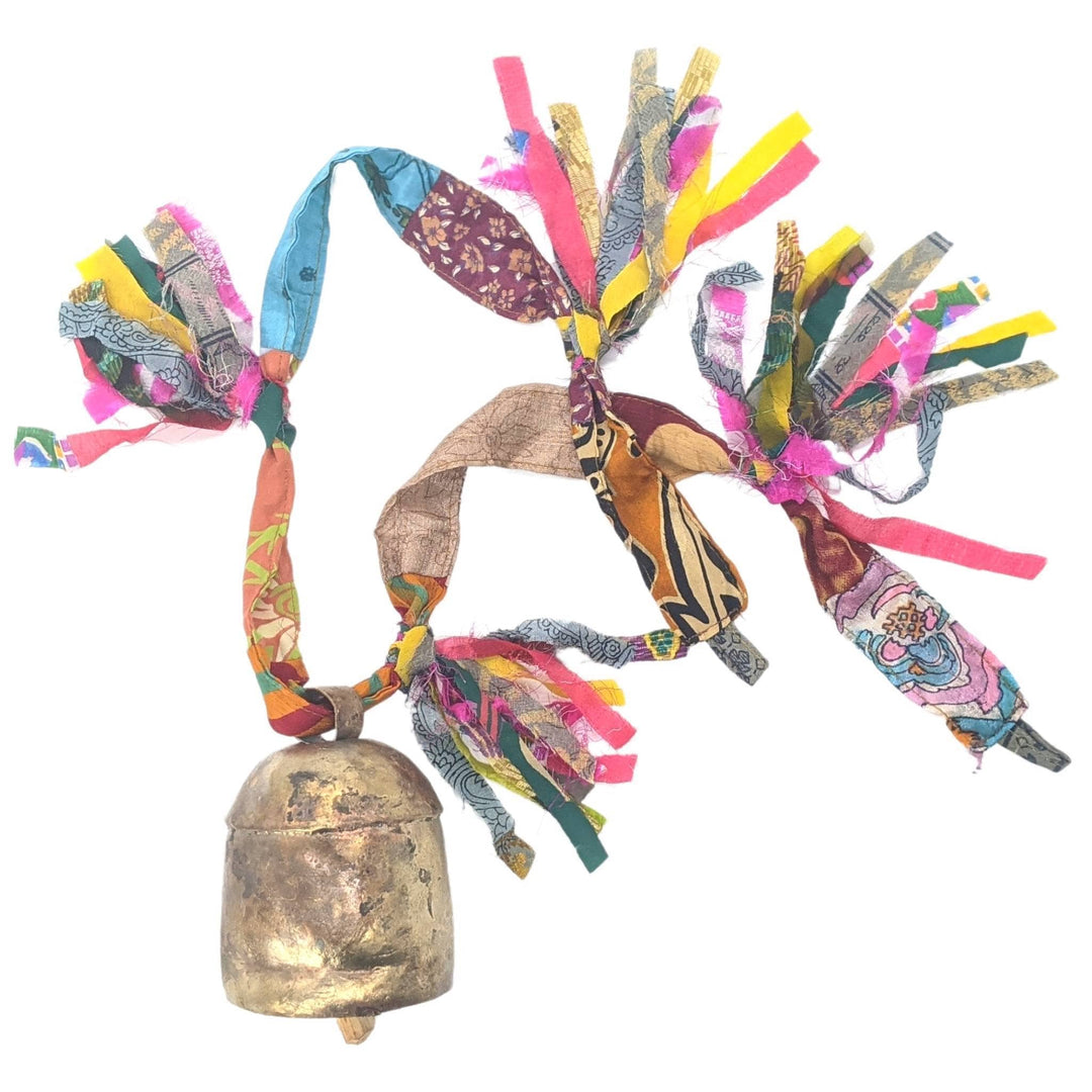 Brassy colored bell with wooden clapper, strung through colorful sari ribbon with 4 fringe tassels in front of a white background.